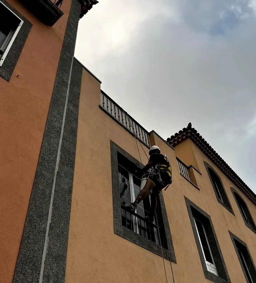 Operario de GSP Servicios descolgado por cuerda trabajando en la fachada de un edificio