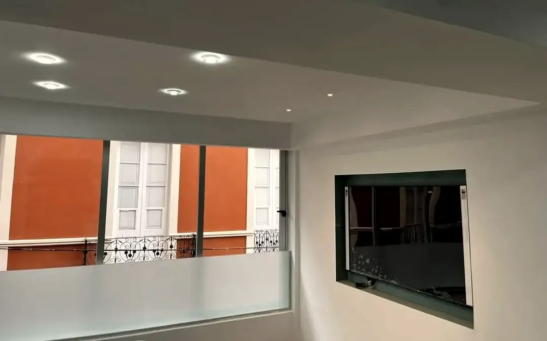 Interior reformado con falso techo, focos empotrados y hueco de ventana
