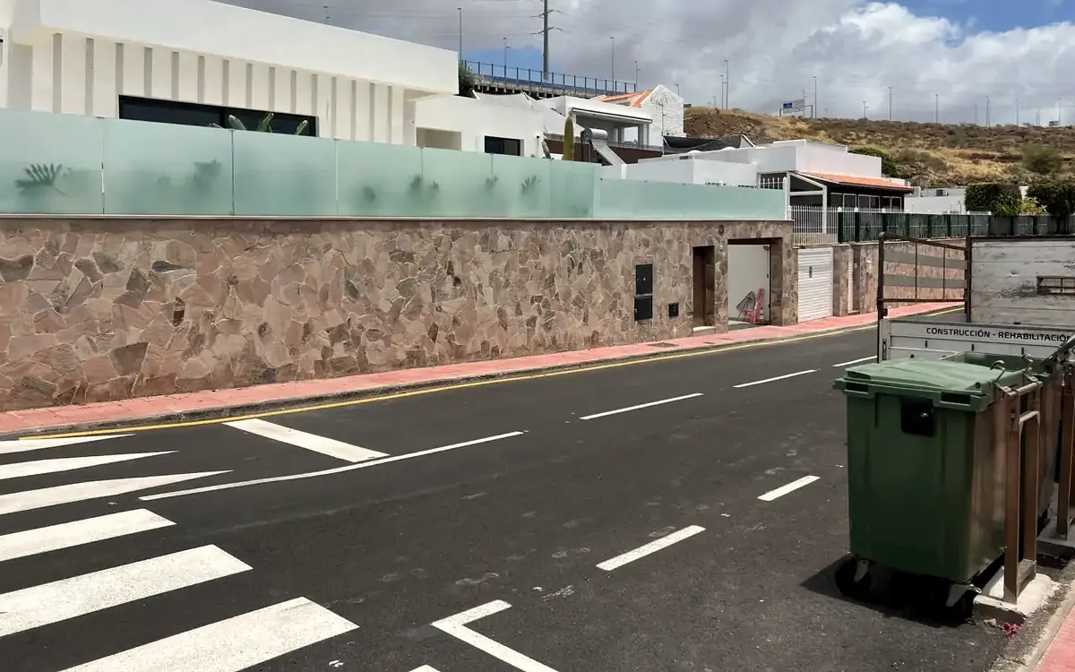 Muro de piedra rematado con barandilla de vidrio a lo largo de una calle