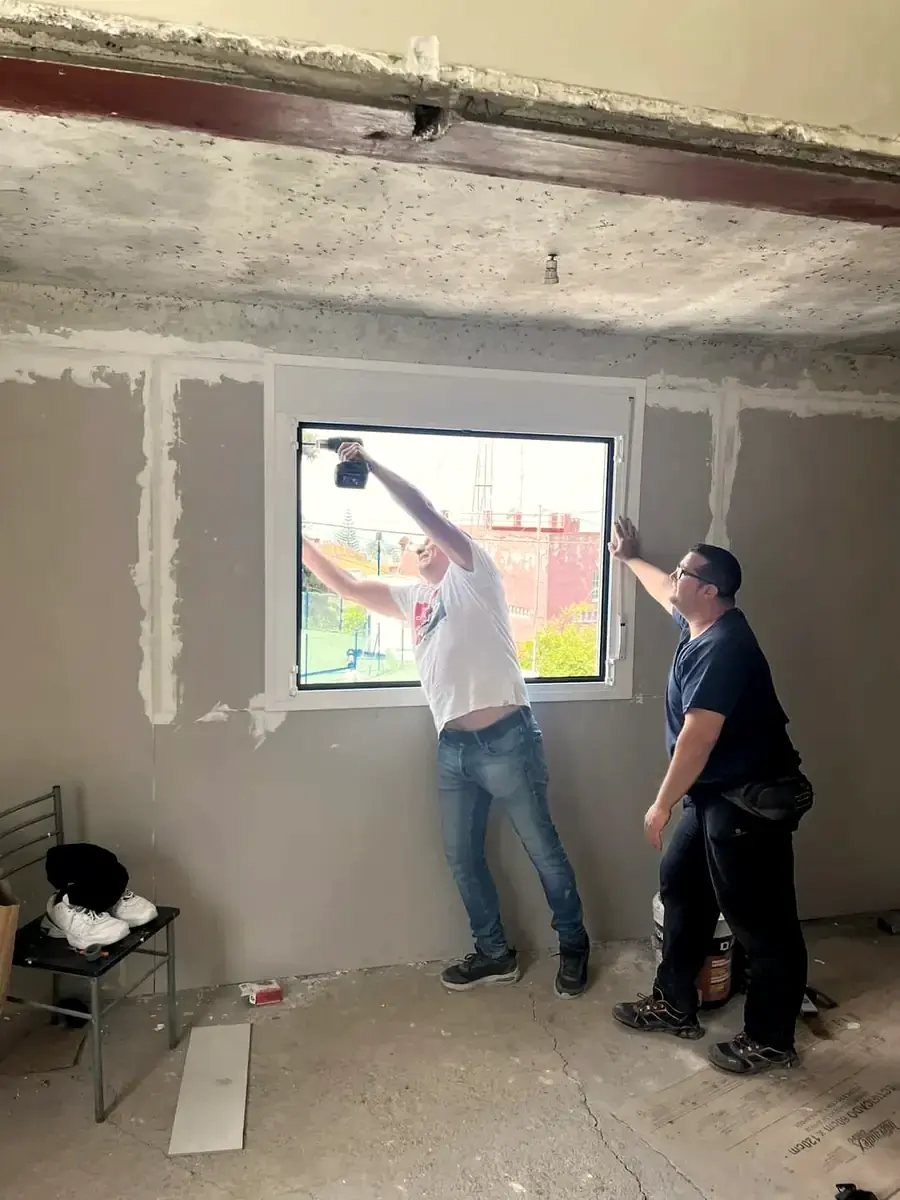 Dos operarios de GSP Servicios instalando una ventana en una vivienda en obra