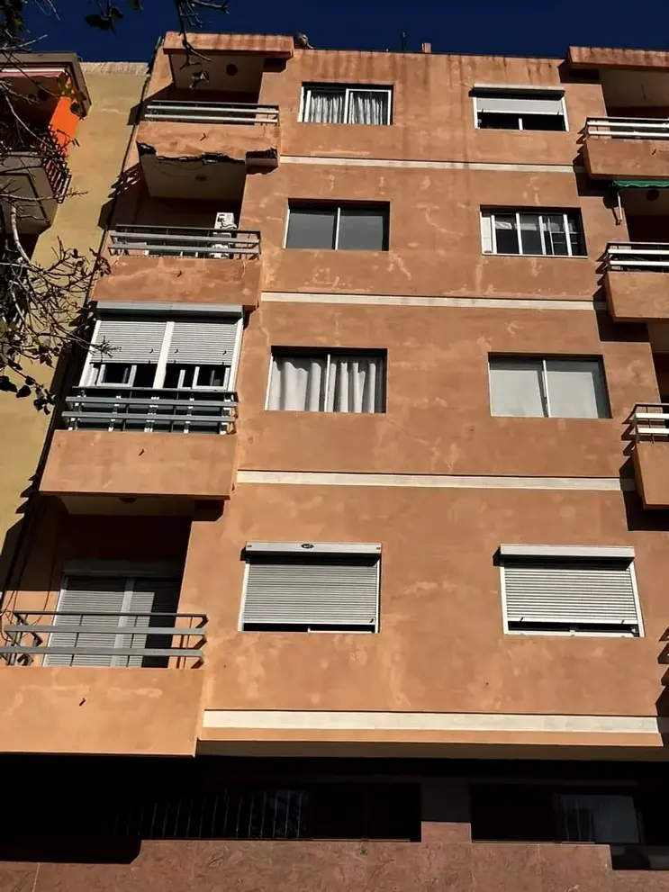 Fachada de un edificio de viviendas de varias plantas con balcones y persianas